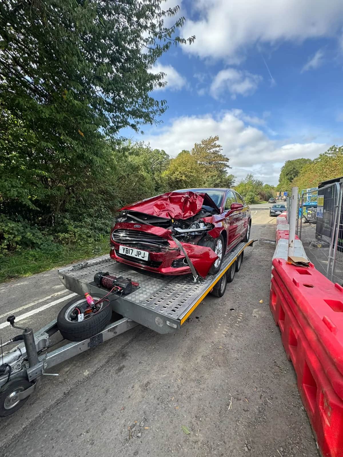 Damaged red car secured to a KYS Recovery trailer